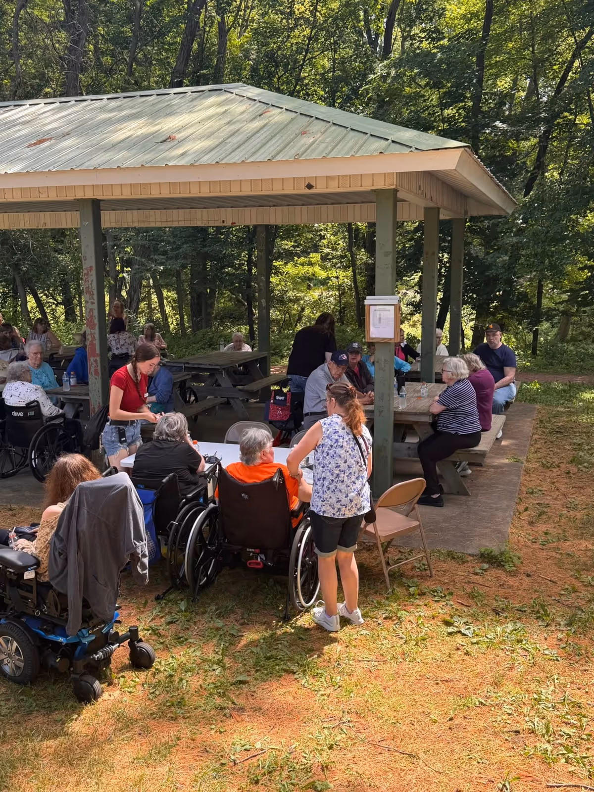 Senior residents and caregivers socialize outdoors under a pavilion at Colfax Senior Living.