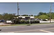 Front exterior of The Woodleigh of Baton Rouge with a parking lot and sign.
