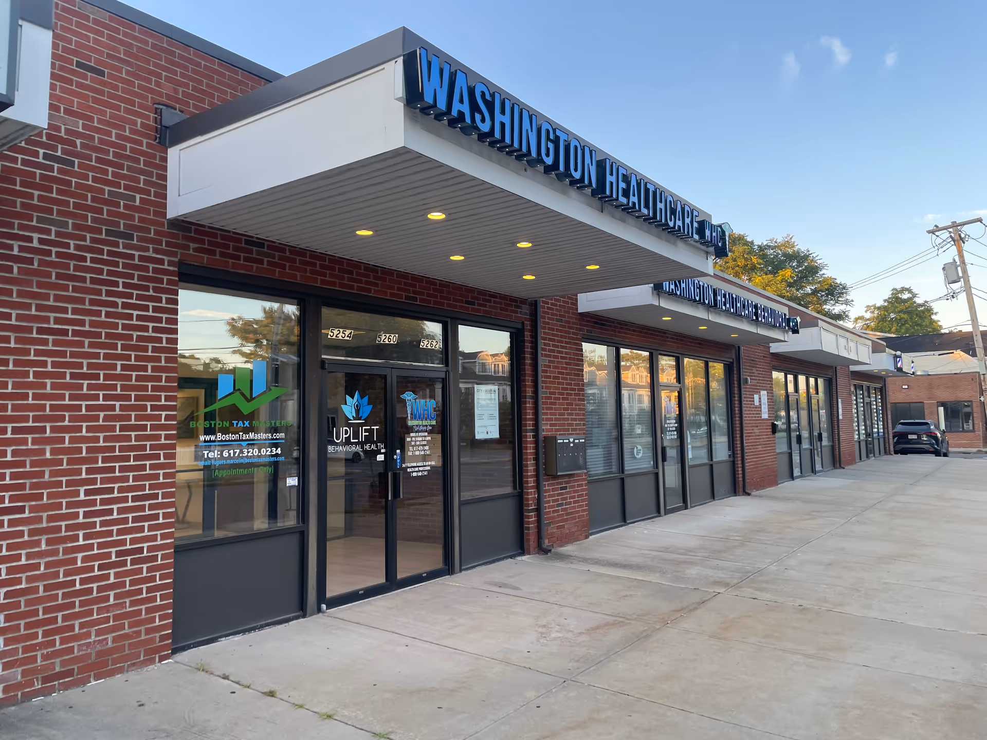 Brick storefronts with glass doors and a blue Washington Healthcare sign under a covered entrance.