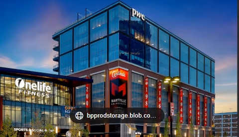 Modern glass-front building exterior with PwC sign and One Life Fitness storefront.