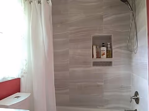 Bright bathroom with tiled shower, built-in niche, and white curtain.
