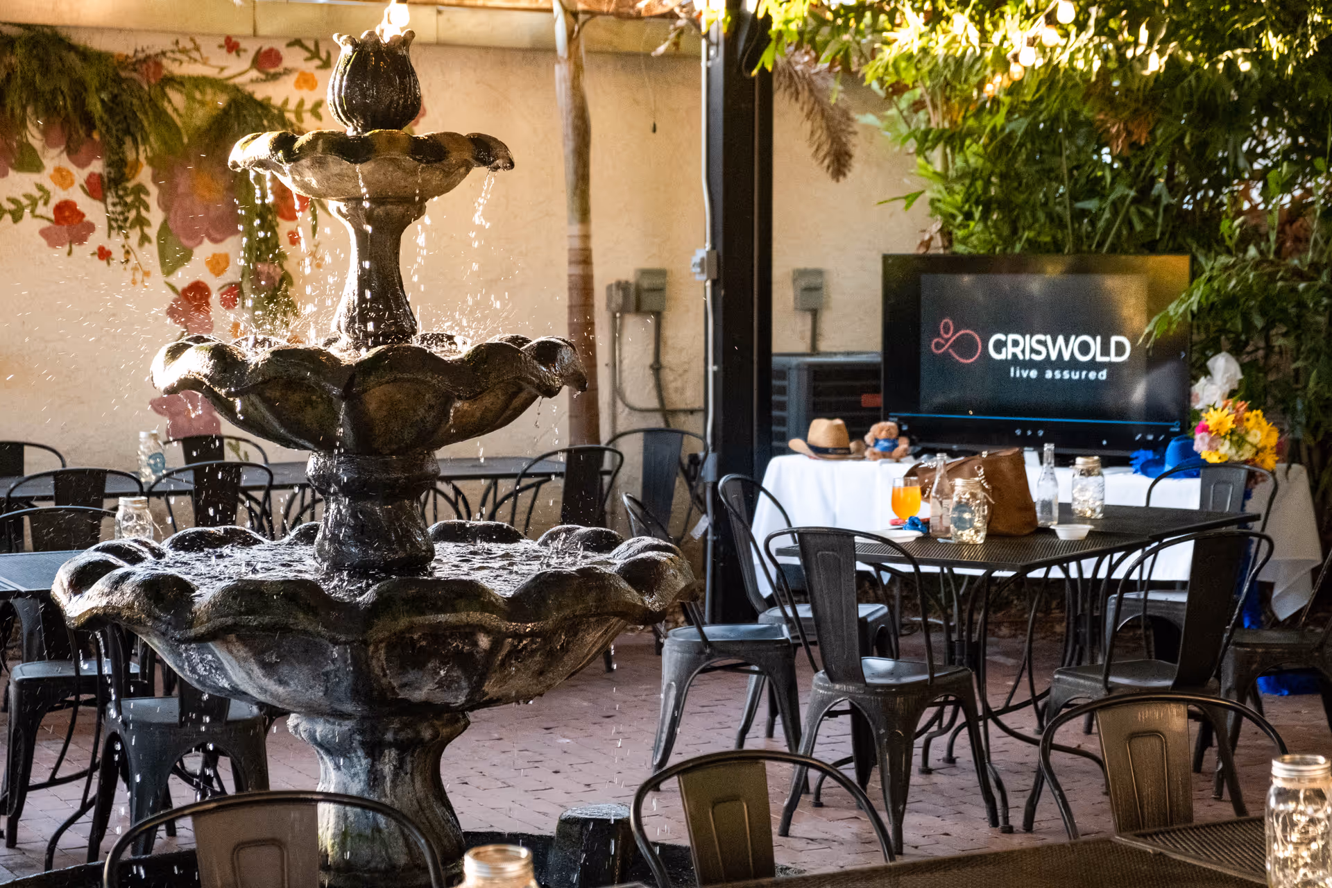 Outdoor courtyard featuring a tiered fountain, metal tables and chairs, and a Griswold screen.