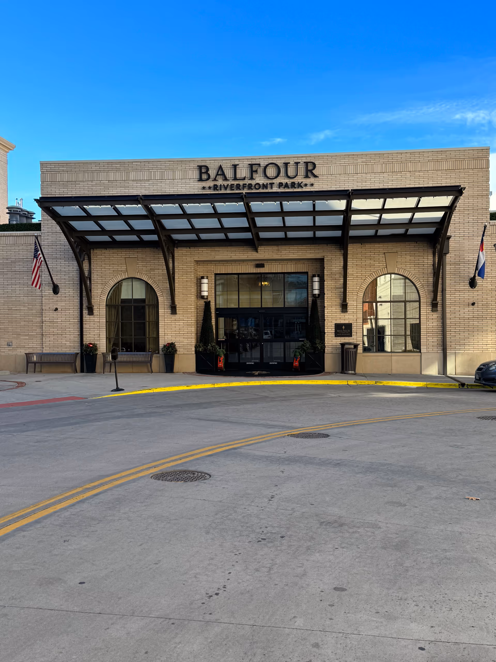 The front of a brick building with a glass canopy labeled Balfour Riverfront Park.