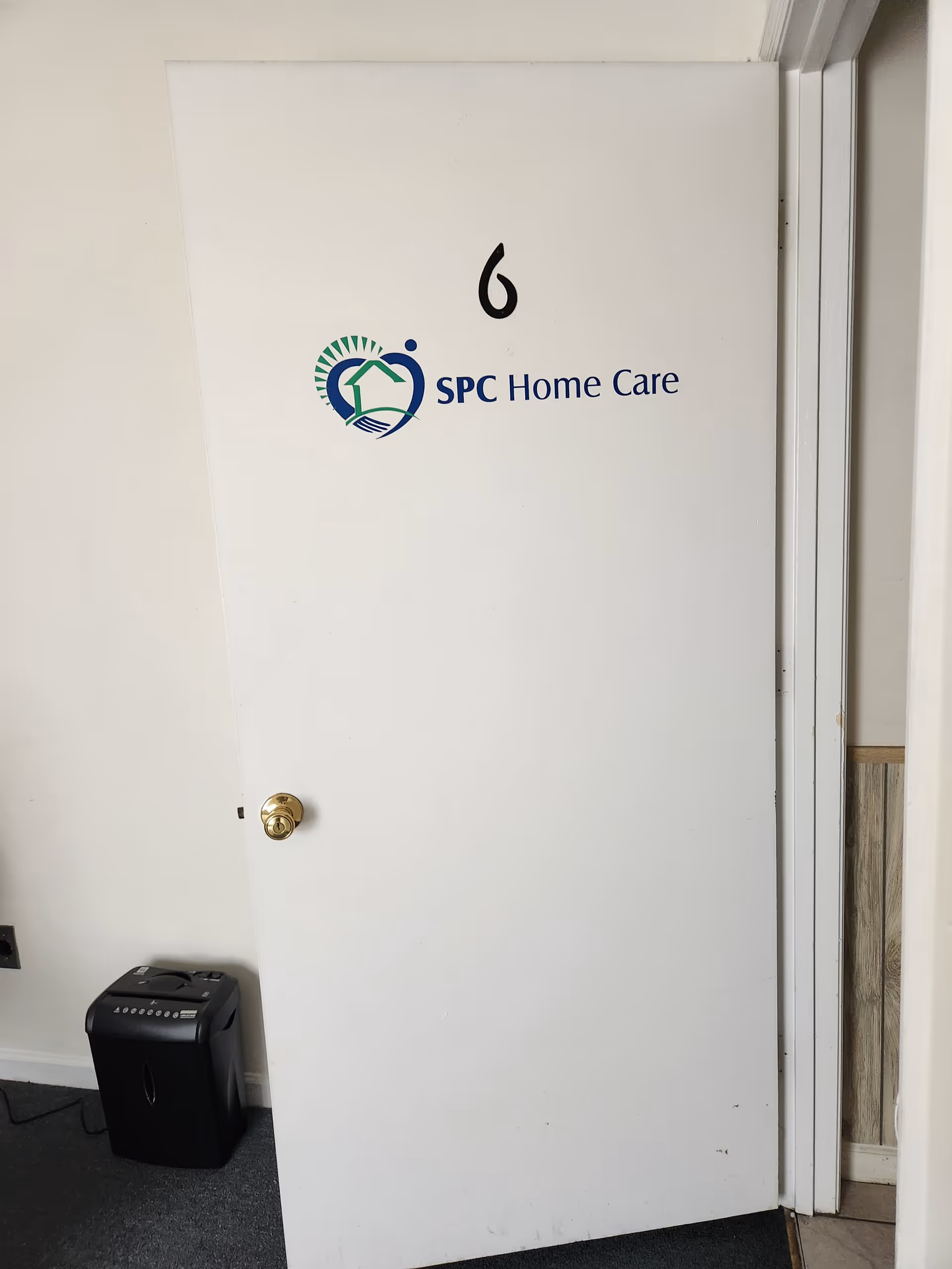 White door with SPC Home Care logo and number 6, in a hallway interior.