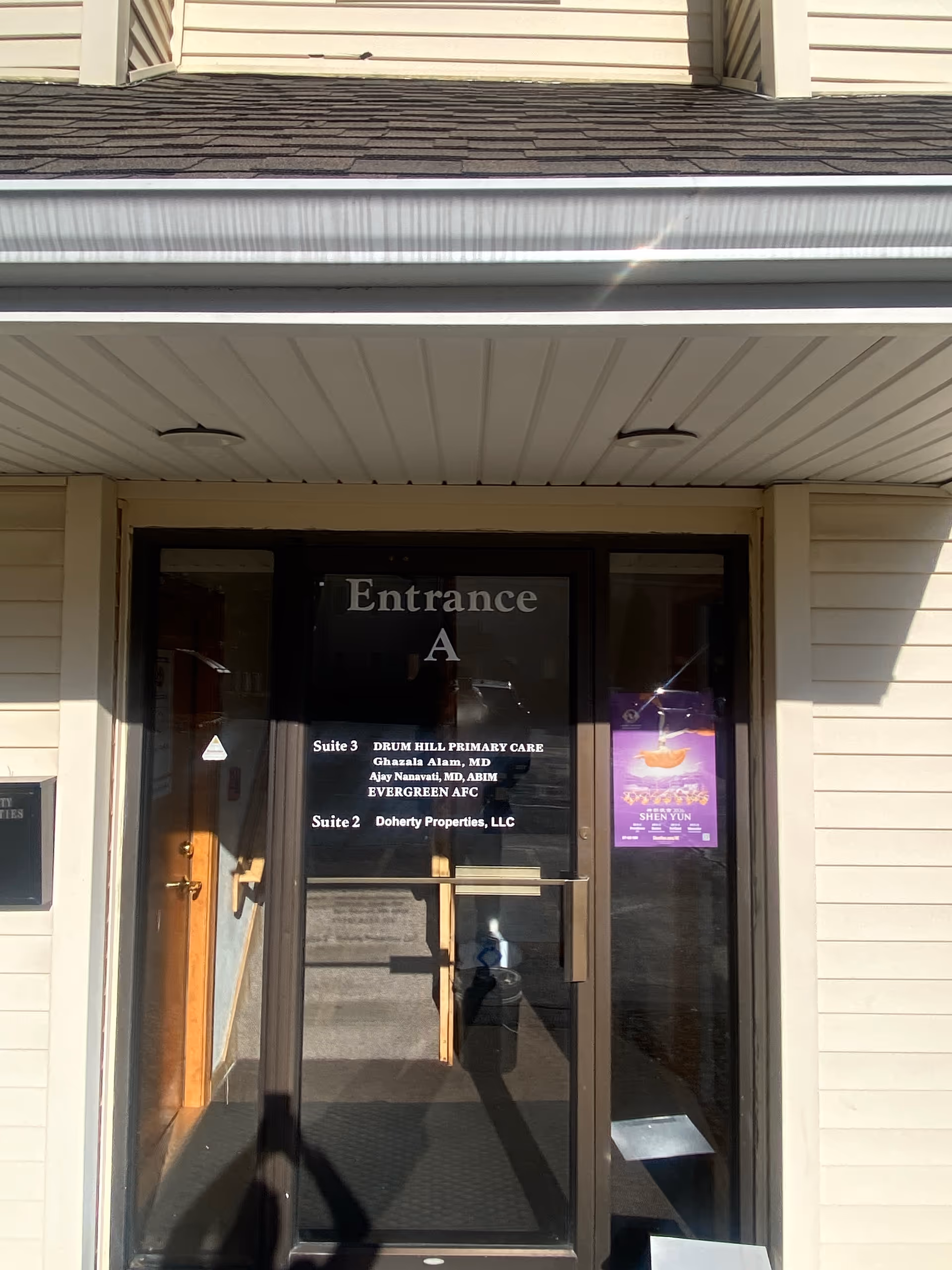 Glass double doors marked Entrance A lead into a beige siding building with posted signs.