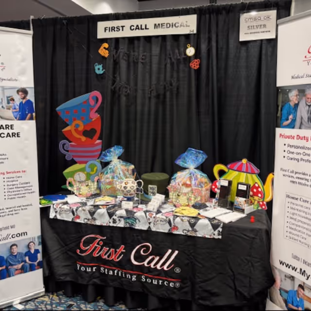 Indoor First Call Medical trade show booth with gift baskets on table.
