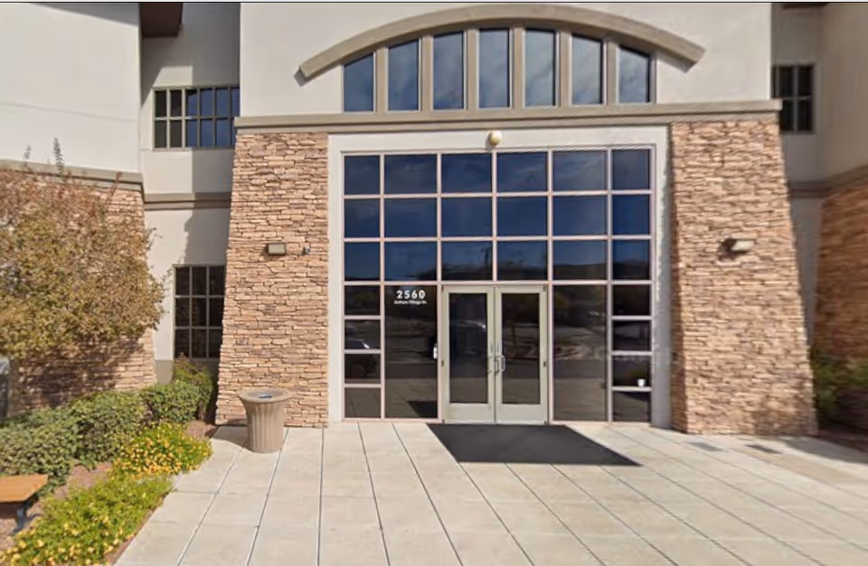 Exterior view of a facility entrance with glass doors and stone facade.
