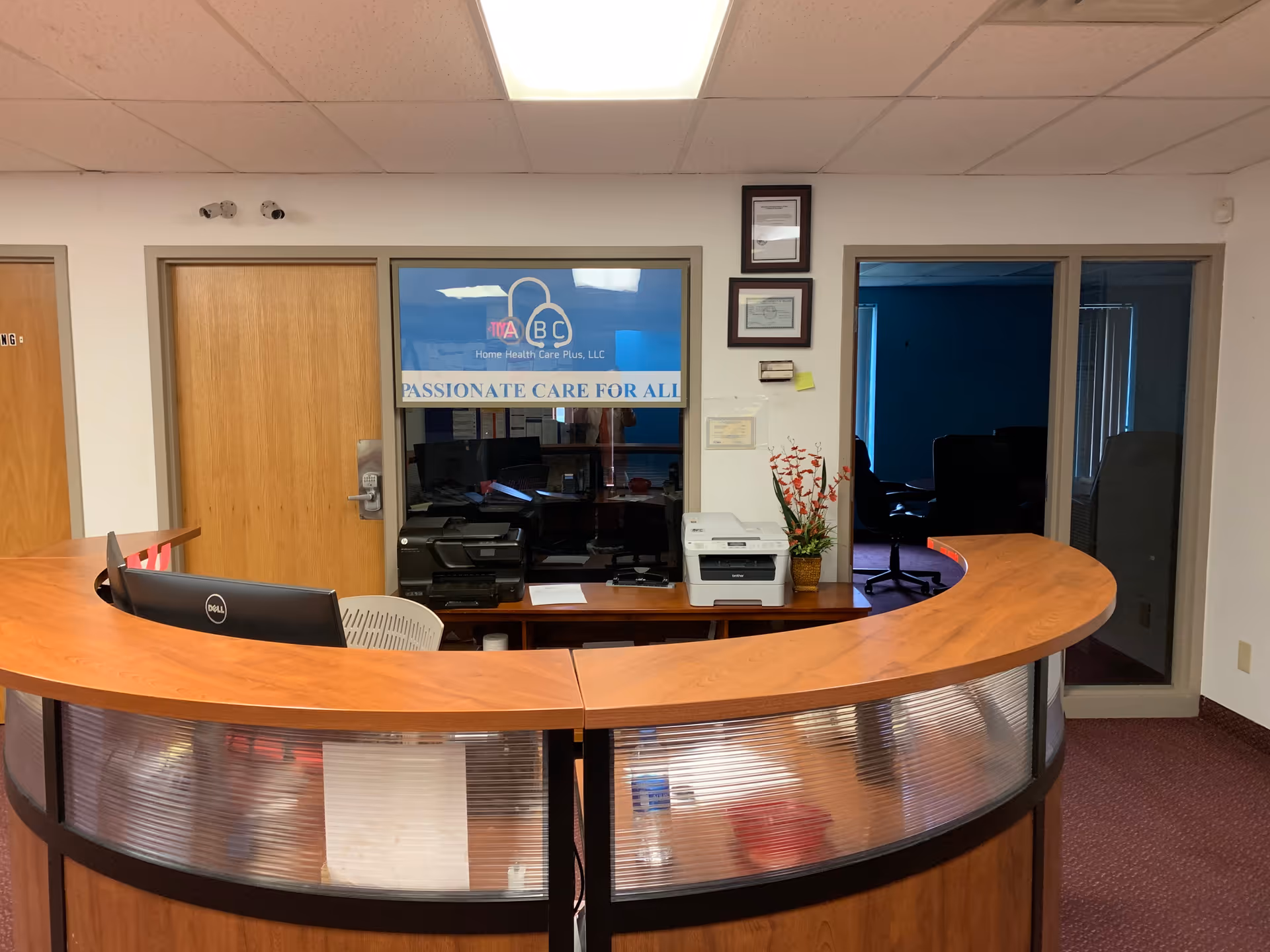 Curved wooden reception desk in a lobby with the ABC Home Health Care Plus sign.