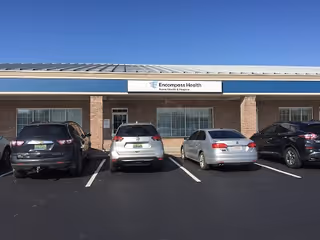 Front view of Enhabit Hospice facility with brick exterior and parked cars.