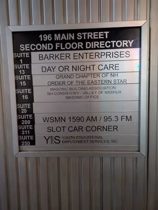 Exterior metal wall with a directory sign listing suites and business names.