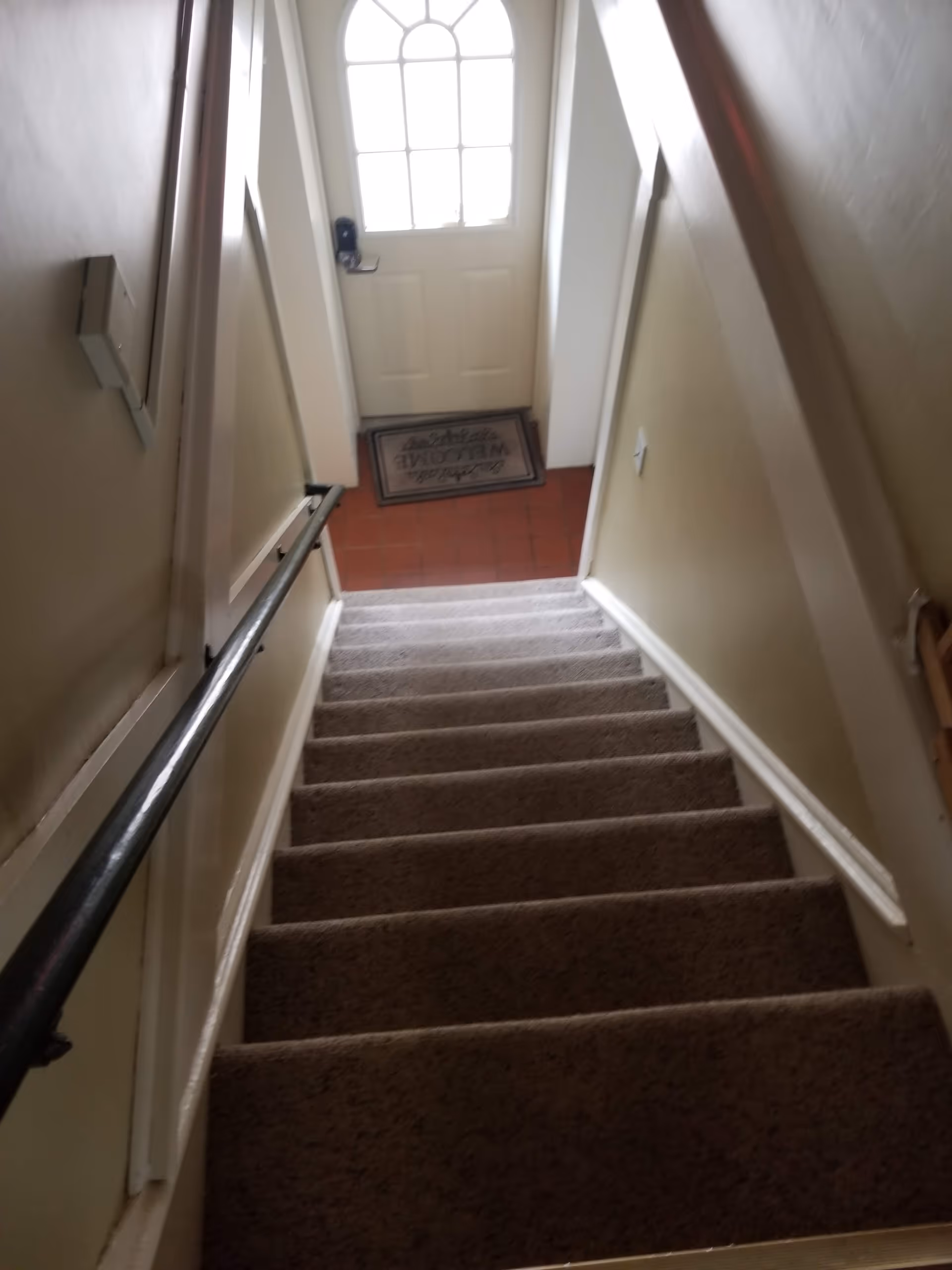 Indoor stairwell in a senior facility, carpeted steps, beige walls, and door at bottom.