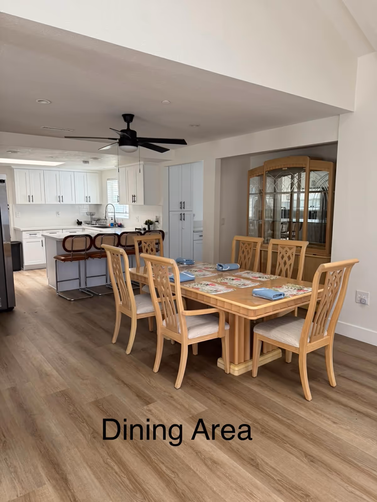 Dining area labeled Dining Area with a large wooden table and white-kitchen background.