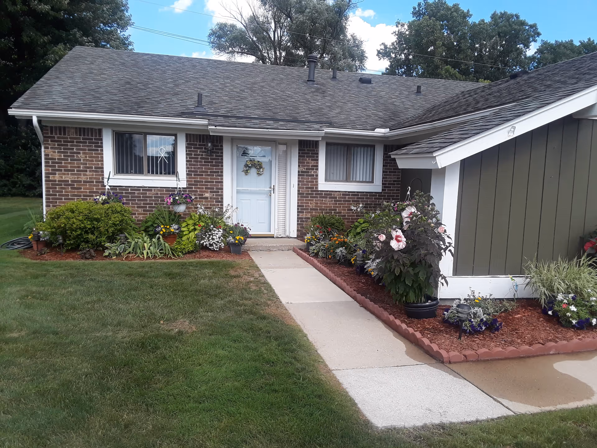 Front view of a brick senior living facility with a garden and walkway.
