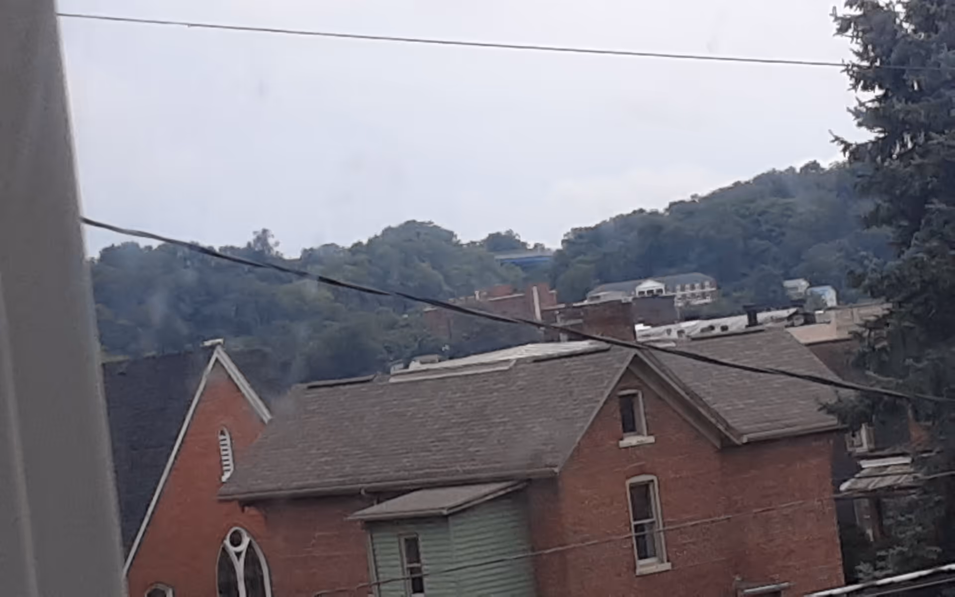 Exterior view of brick houses with wires and hills in the background.