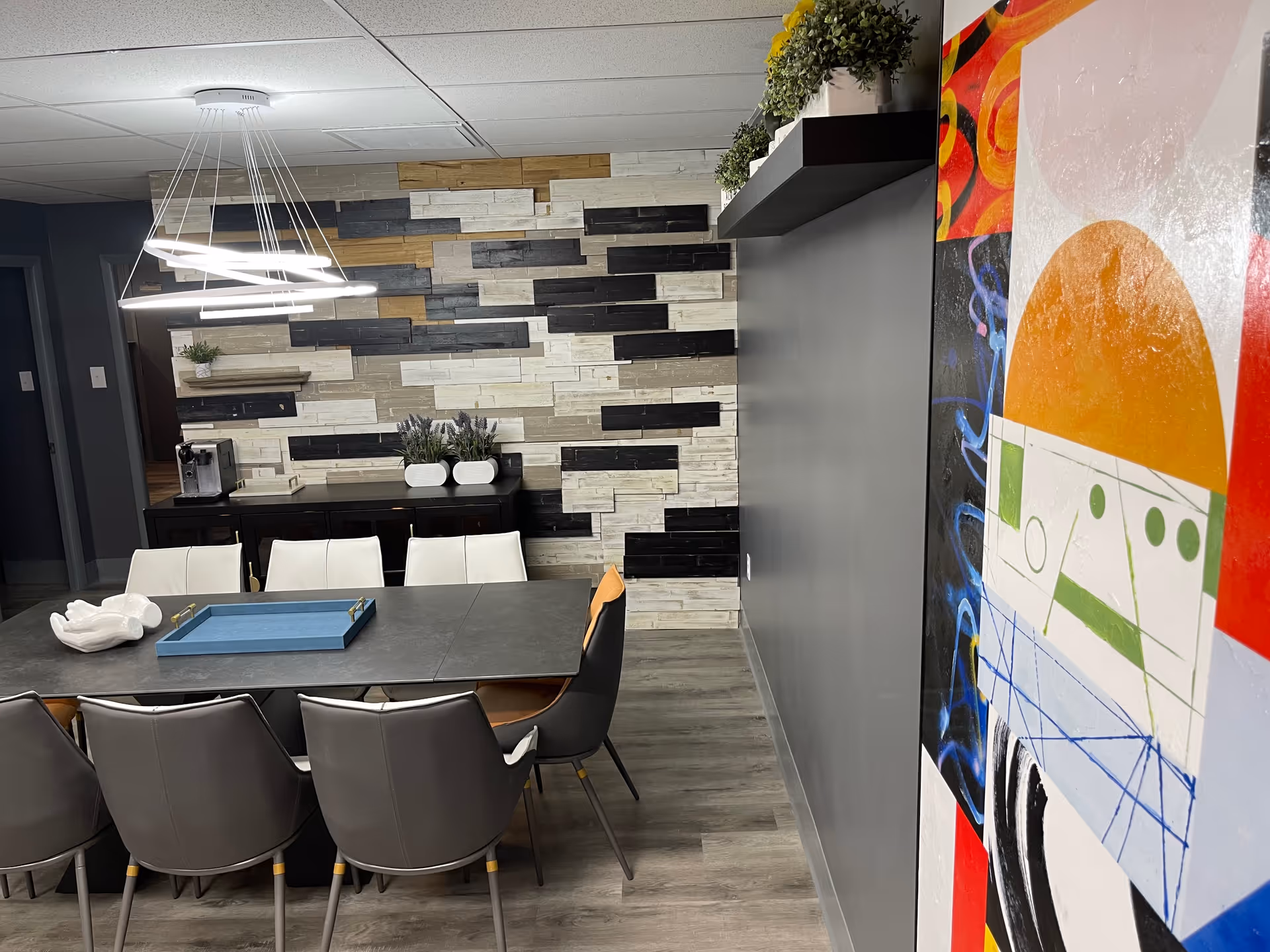 Modern dining area featuring a long table, multiple chairs, and a stone-patterned accent wall.
