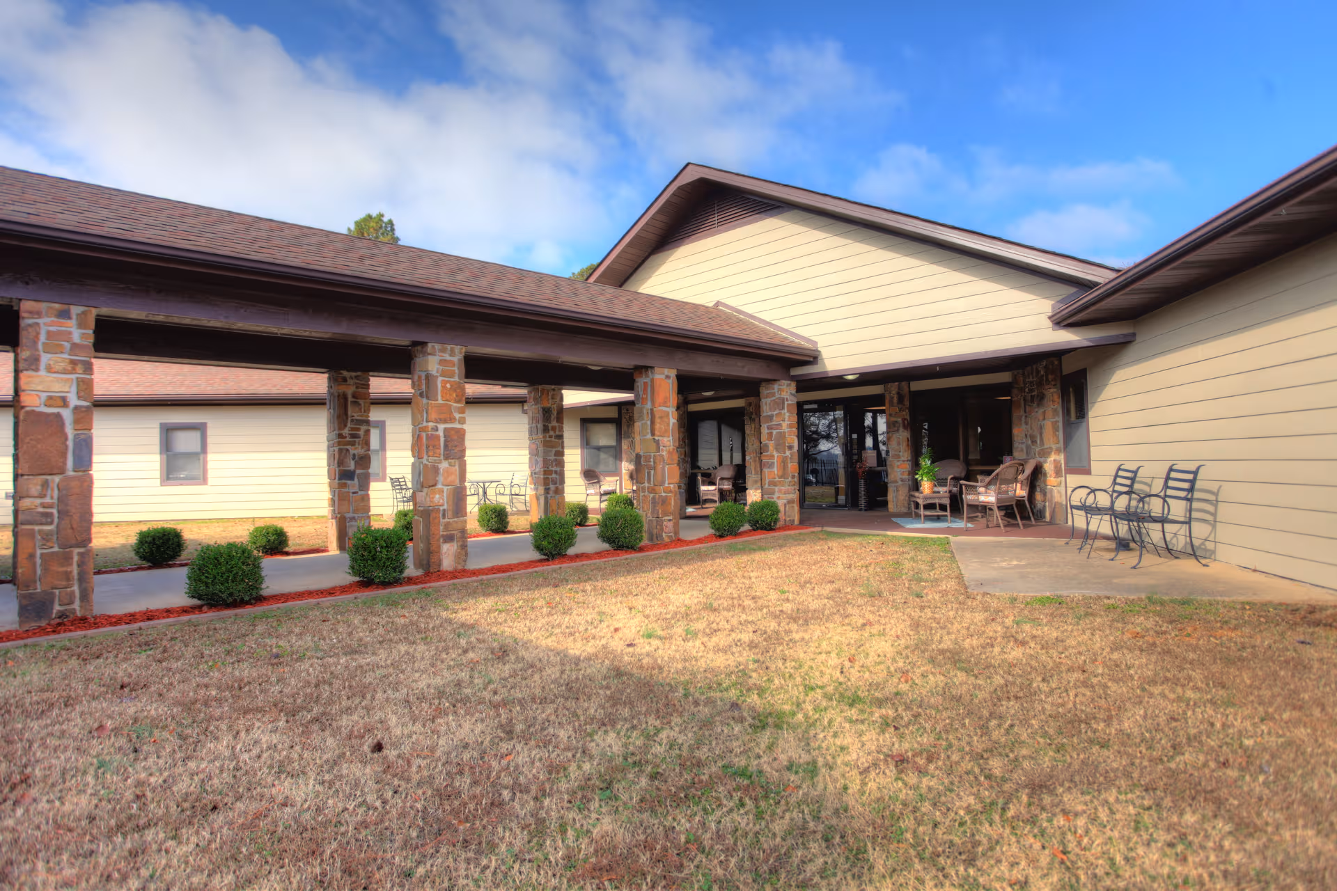 Exterior view of Pines Nursing and Rehab Center entrance with covered walkway and seating.