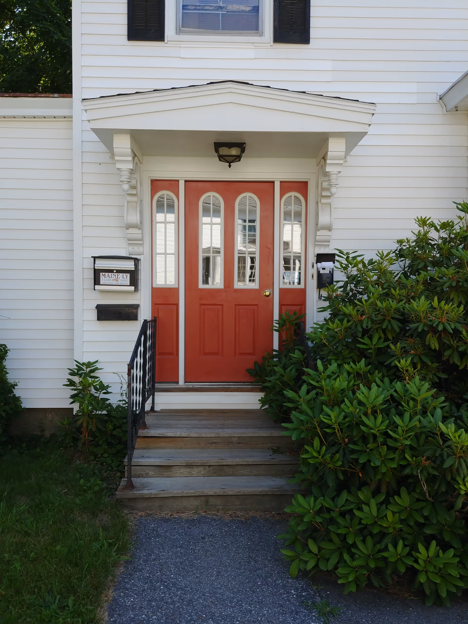 White building front with red double doors and steps at Maine-ly Elder Care entrance