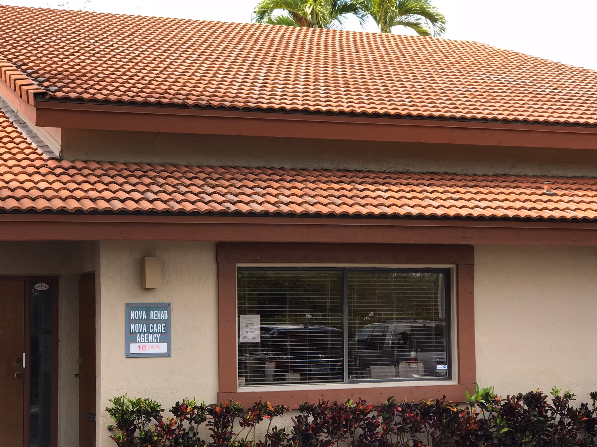 Exterior of a single-story building with red-tiled roof; sign reads Nova Care Agency.
