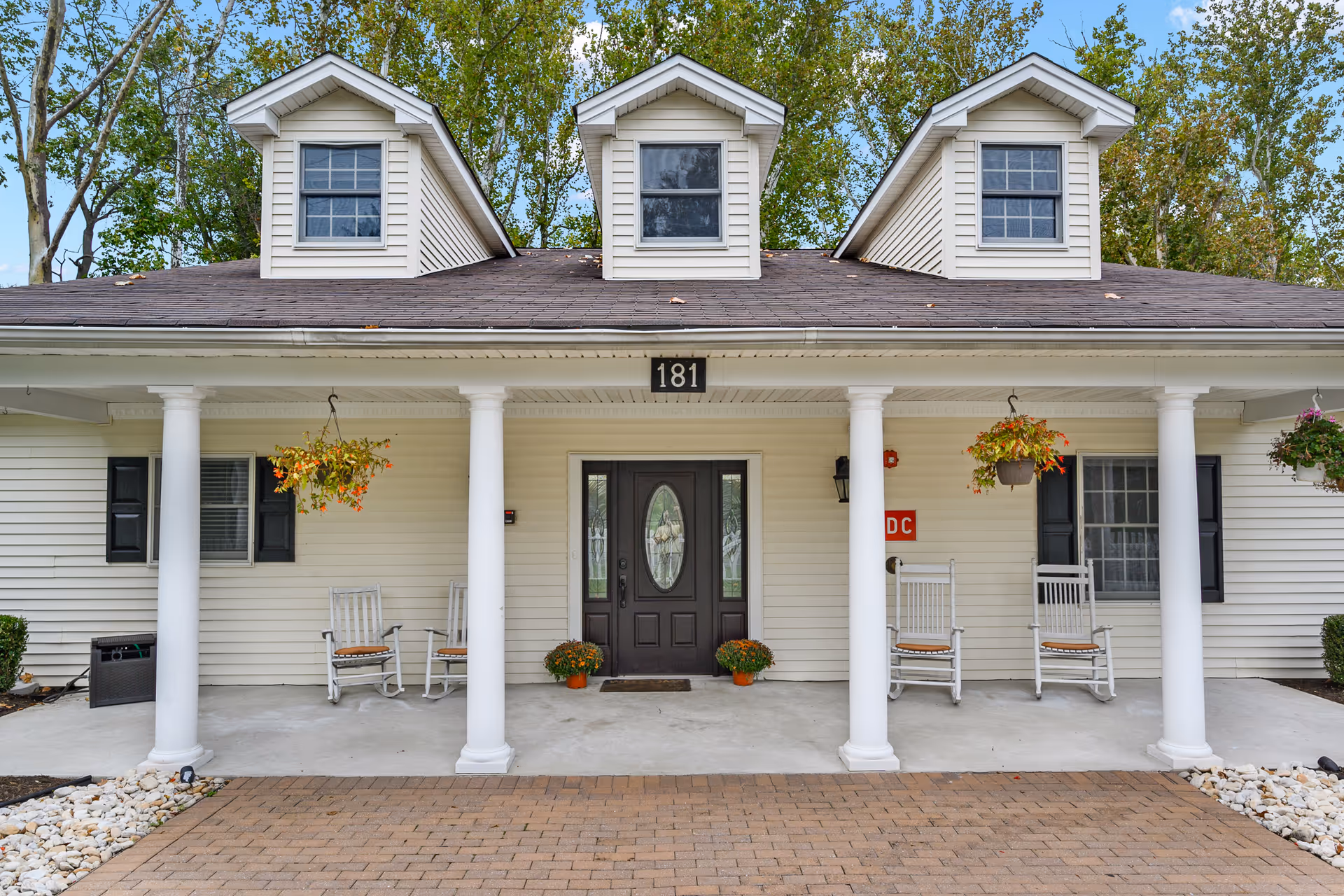 Front view of Fox Trail Memory Care Living with porch chairs and hanging baskets.