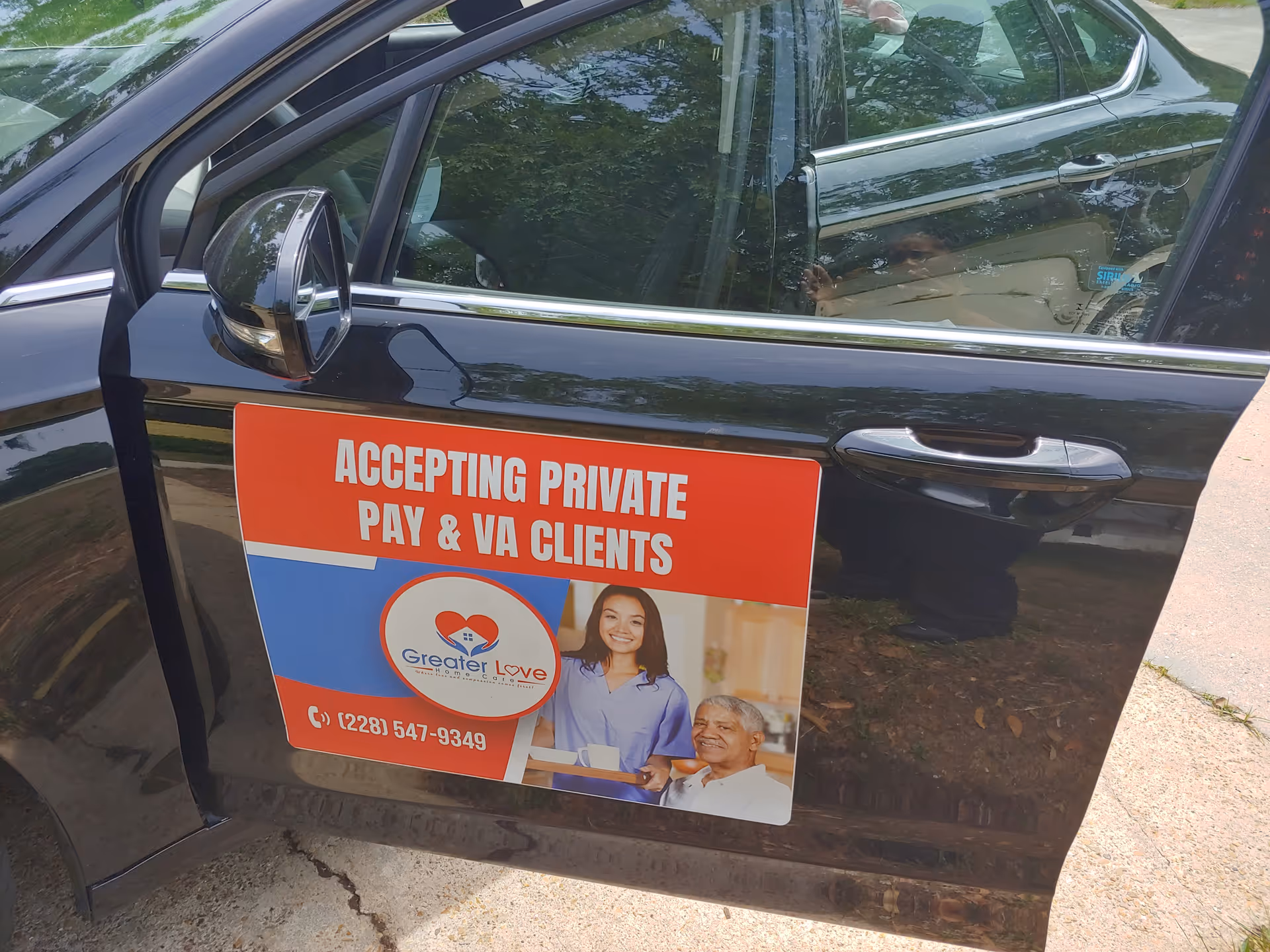 Car door displaying 'Accepting Private Pay & VA Clients' sign for Greater Love Home Care.