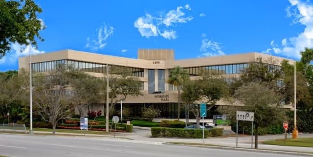 Exterior view of the Interstate Plaza building with trees and a street in front.