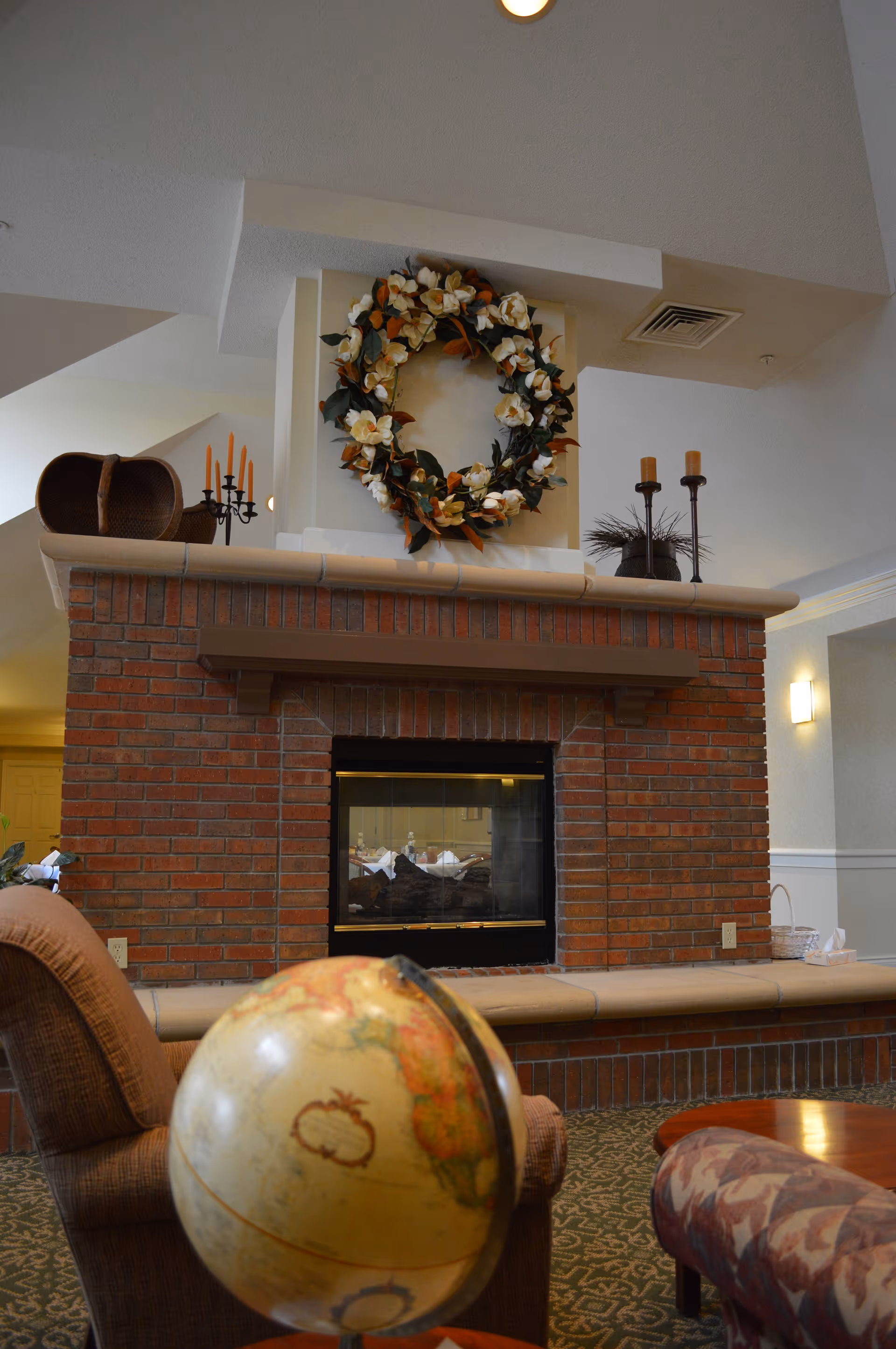 Brick fireplace with a wreath in a cozy Credo Senior Living lobby lounge.