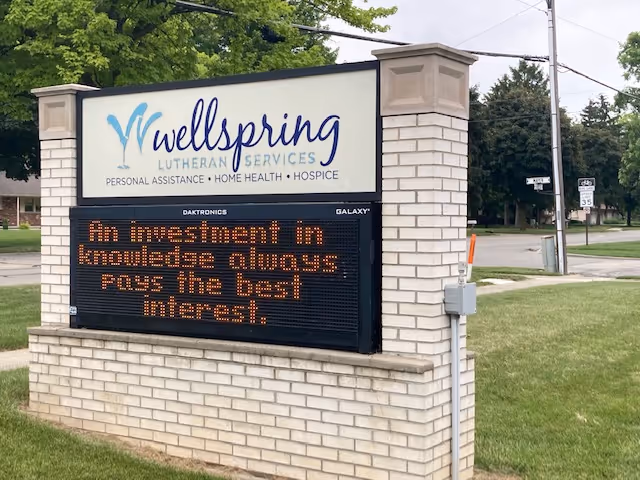 Exterior sign for Wellspring Lutheran Services on a brick pedestal.
