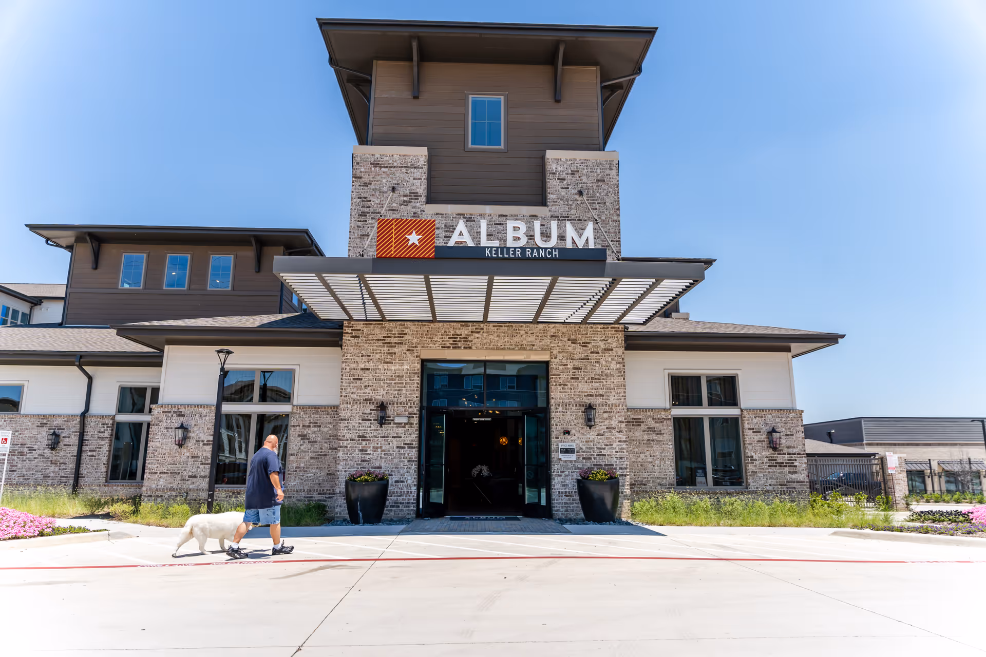 Exterior view of Album Keller Ranch facility with stone entrance and man walking a dog.
