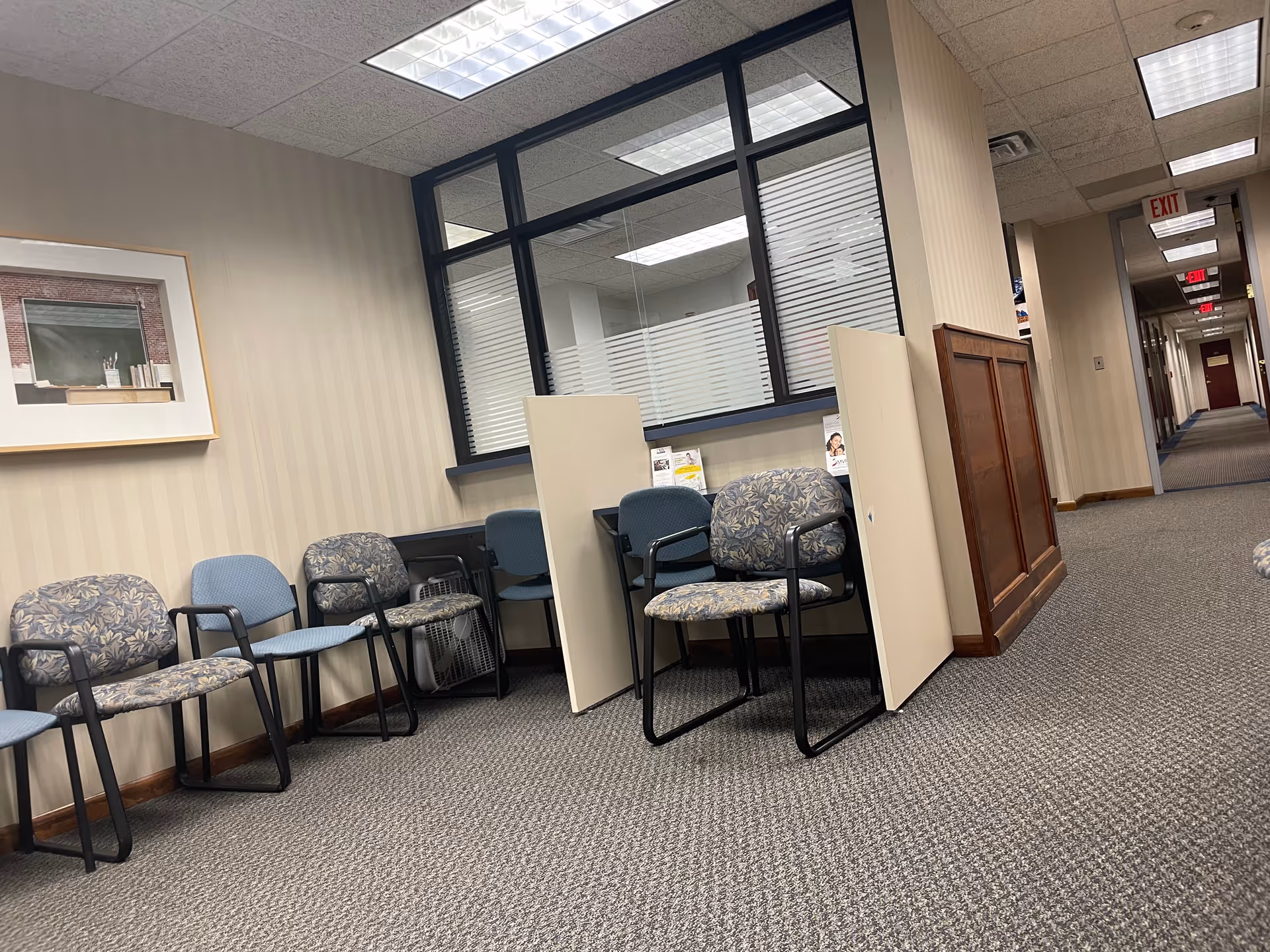Office-like waiting area along a hallway with chairs and partitions.