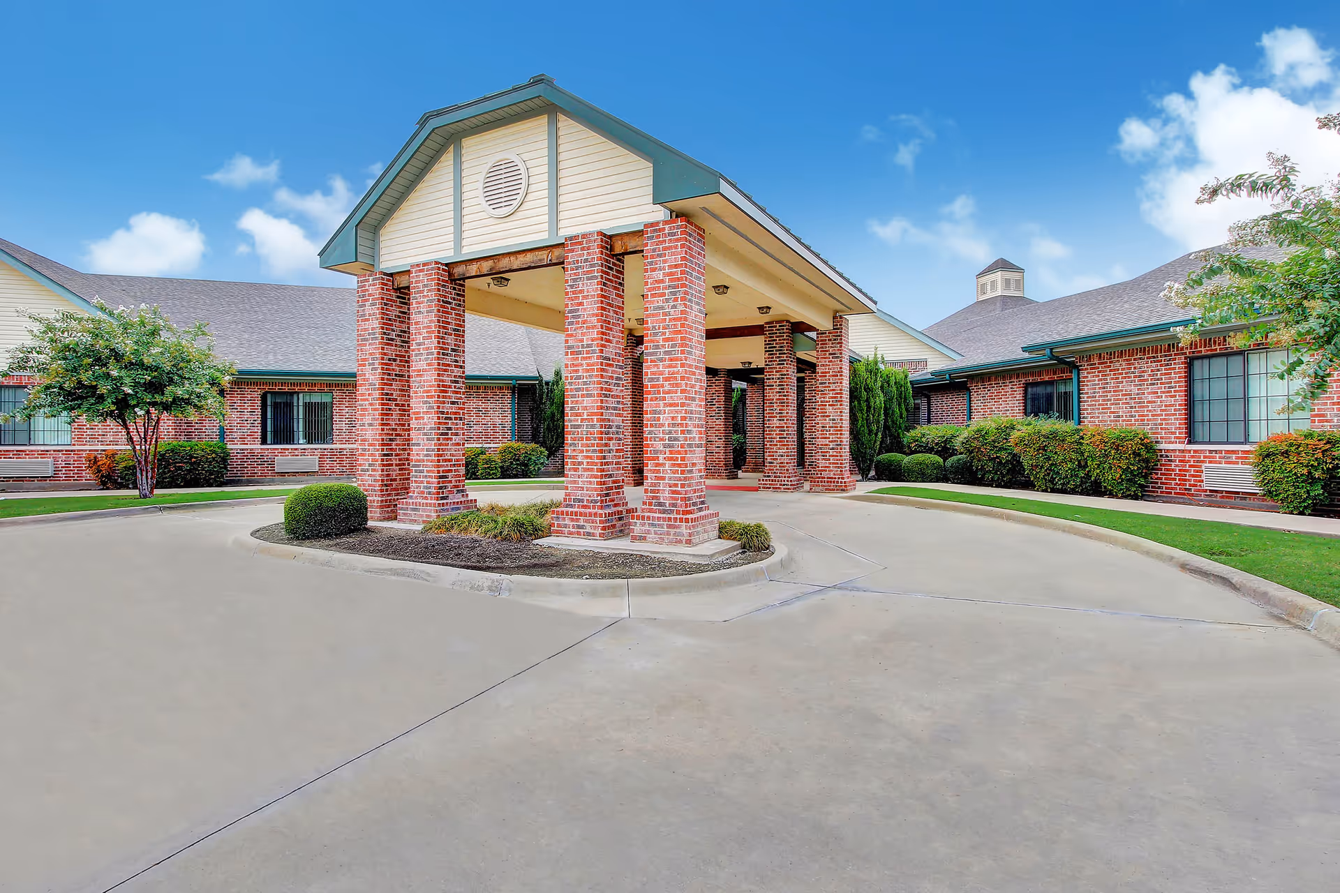 Brick healthcare facility exterior with a covered front entrance and brick columns.