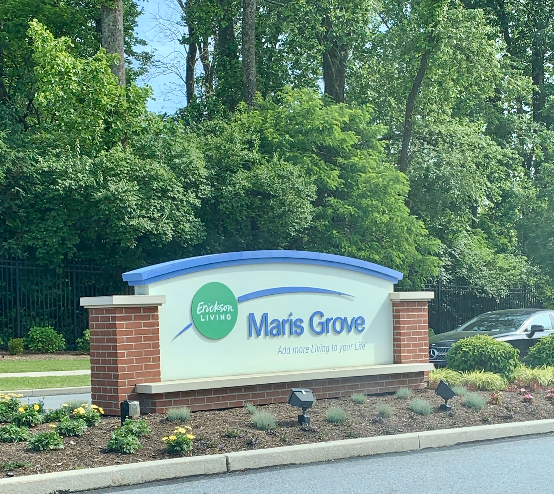 Exterior sign for Maris Grove senior living with brick base and landscaping.