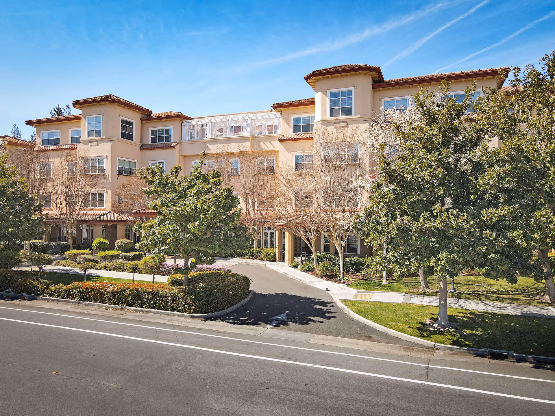 Sunrise of Sunnyvale exterior building with landscaped entrance and trees.