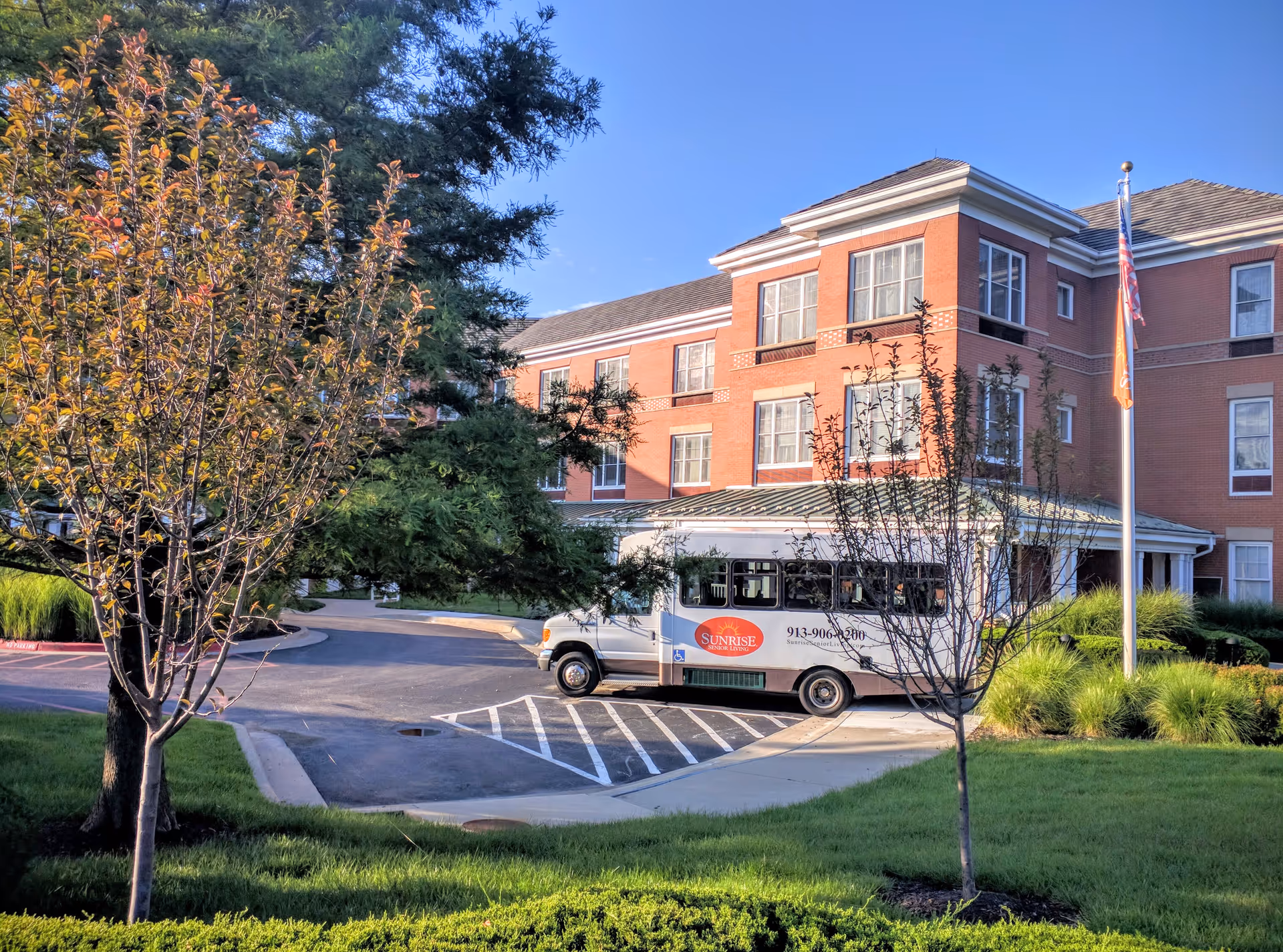 Exterior view of Sunrise of Leawood building with a parked shuttle bus.