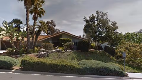 A single-story facility with manicured front yard landscaping and palm trees.