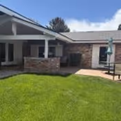Exterior view of Aspen Home for Seniors facility with brick accents, covered entry, and green lawn.