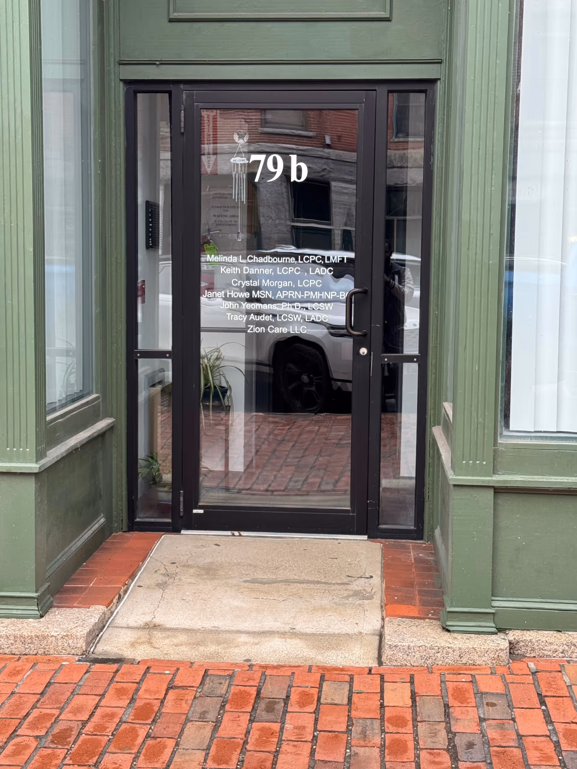 Green-framed building entrance with glass door displaying '79b' and Zion Care.