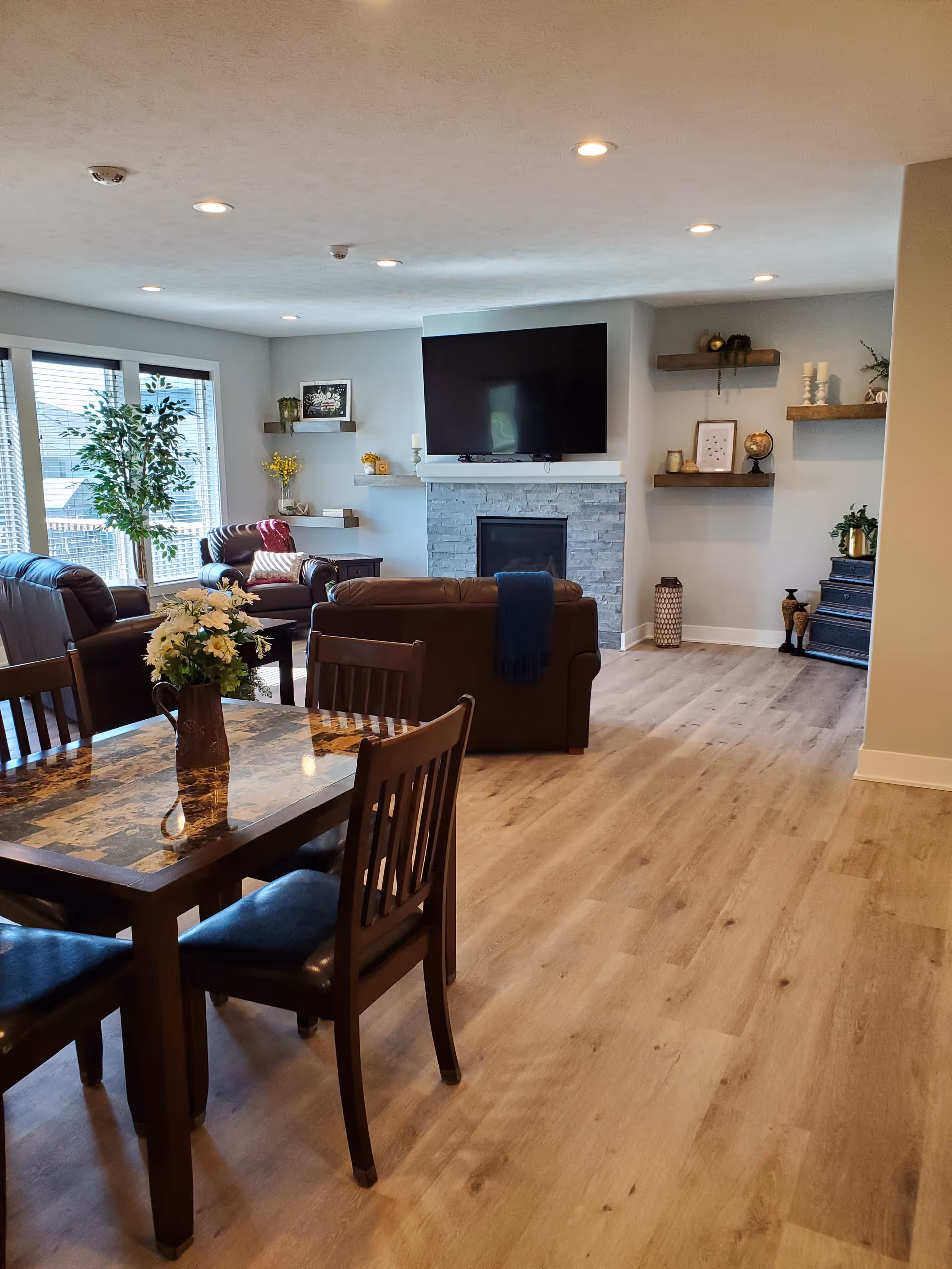 Open living area with a fireplace, mounted TV, and brown leather seating.
