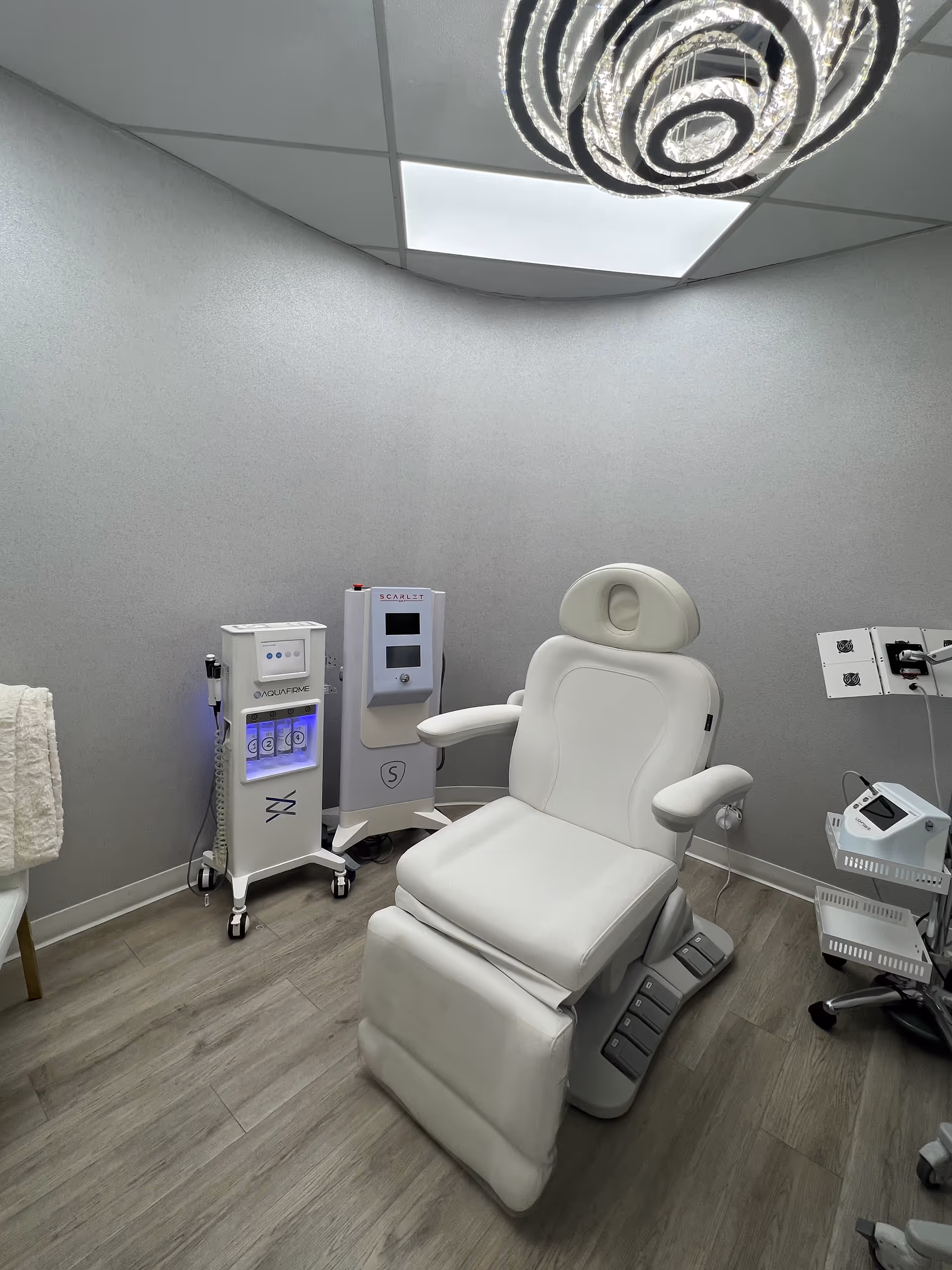 A white reclining medical chair with devices in a sterile clinical treatment room.