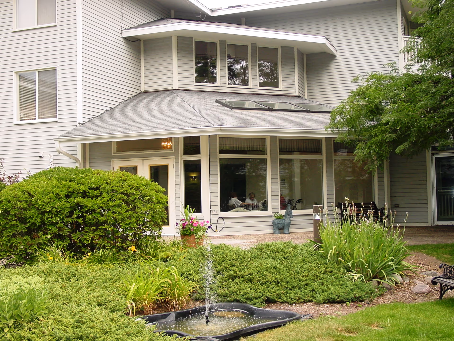 Exterior view of Laurel Oaks Senior Living with landscaped garden and fountain.