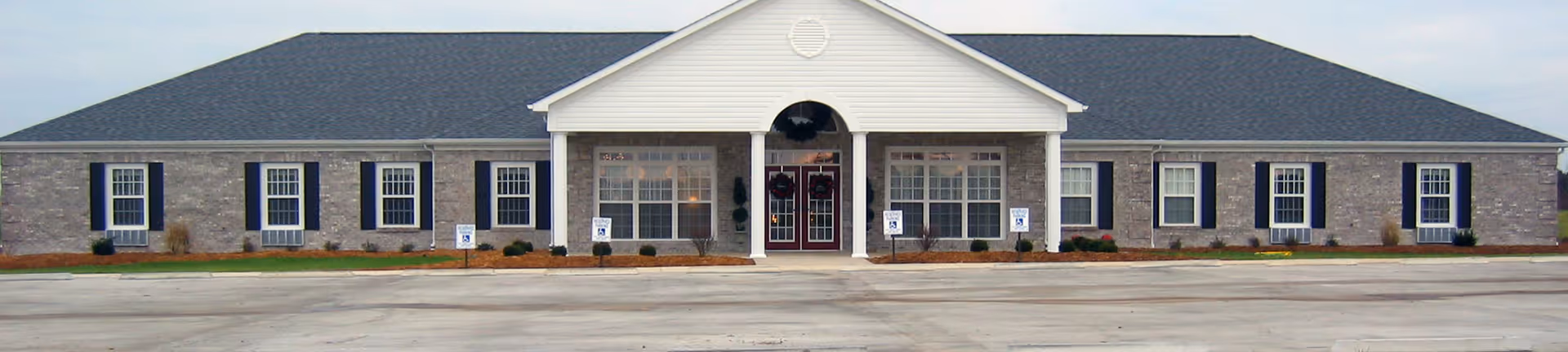 Exterior view of Licking Residential Care, a single-story brick senior living facility with a centered entrance.