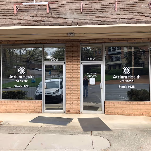 Brick storefront with large glass doors displaying Atrium Health At Home Stanly HME signage.