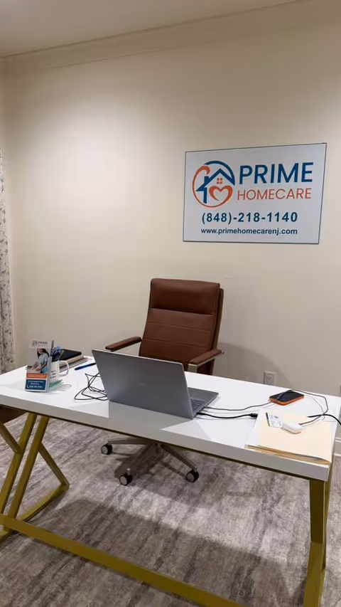 Office desk with laptop and a Prime Homecare sign on the wall.