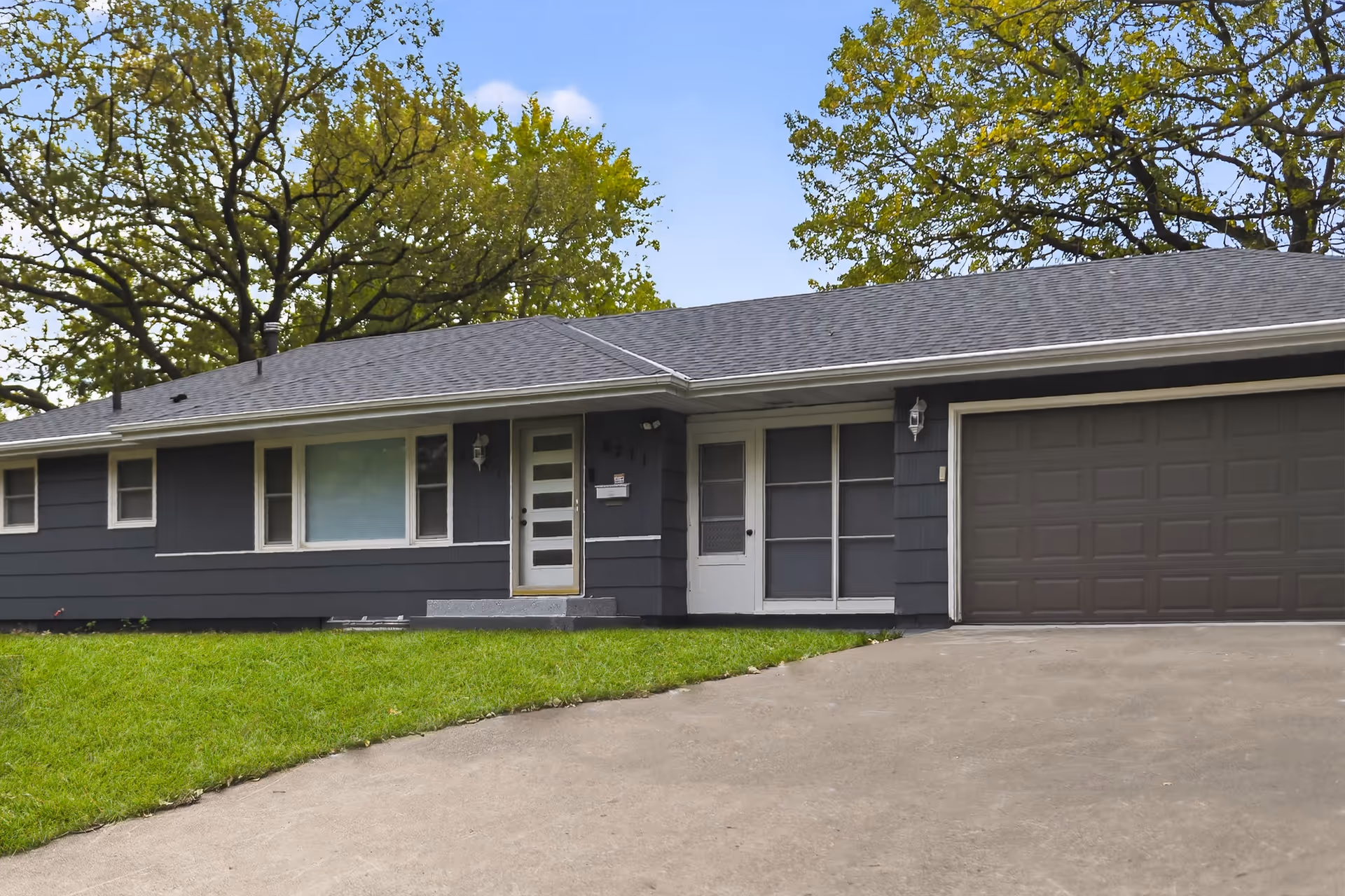 Front view of a single-story gray facility with garage, entrance, and green lawn.