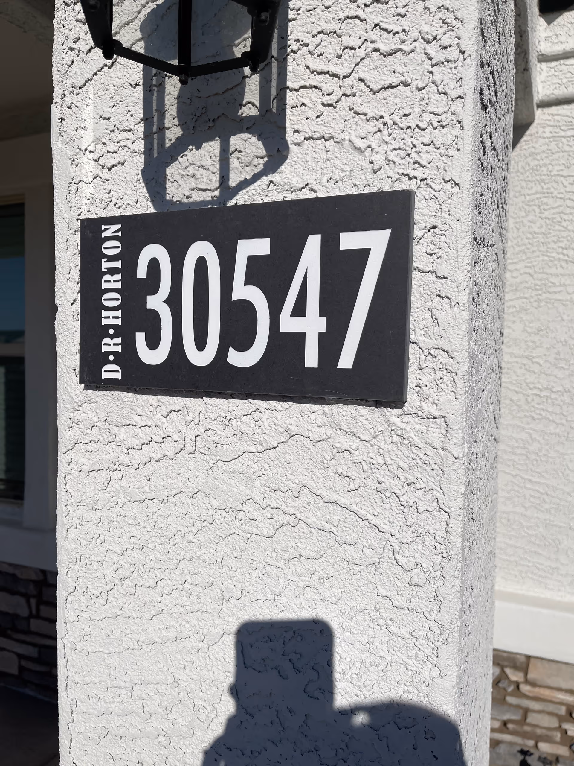 Close-up of a textured exterior wall with a large address plaque reading 30547.