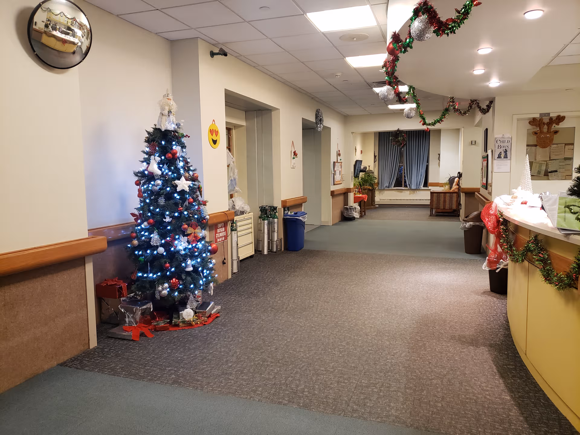 Hallway of a senior living facility decorated with a Christmas tree and garlands.
