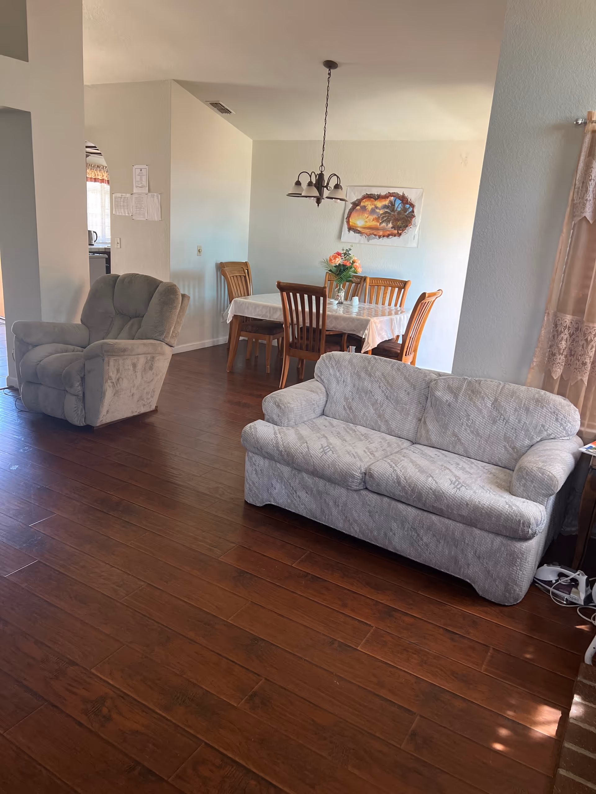 Cozy living room with wood floors, two sofas, a recliner, and a dining table.