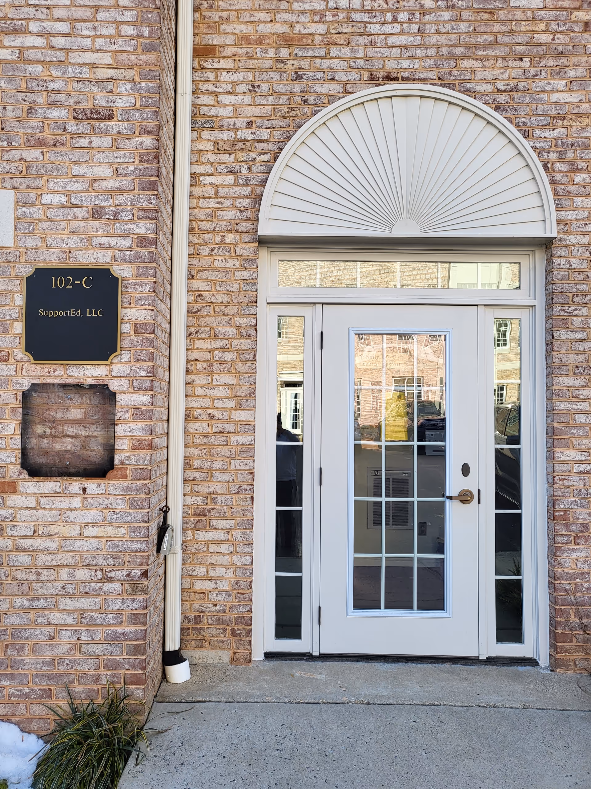 A brick building entrance with glass double doors and an arched transom above.