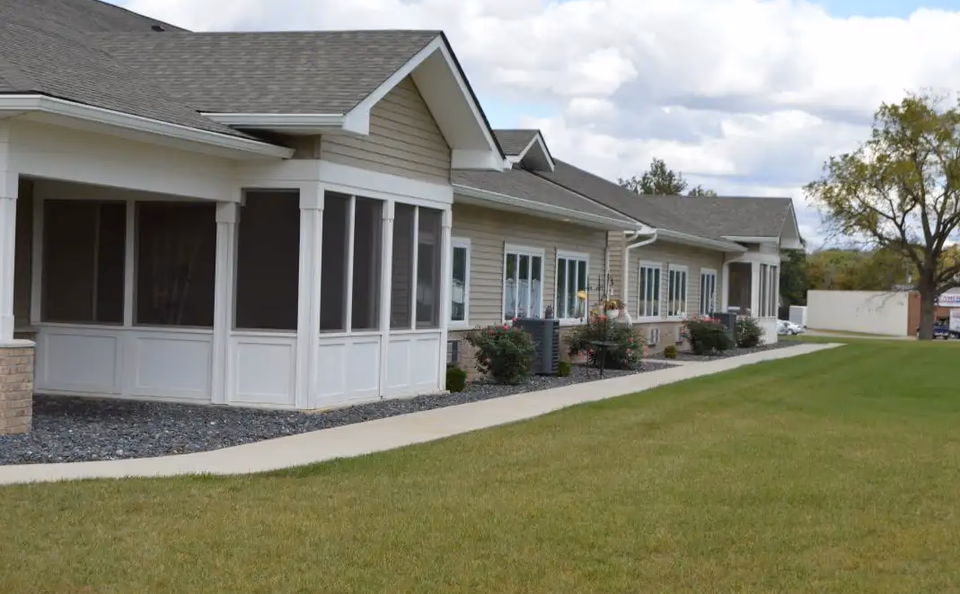 Single-story assisted living building with screened porches and a green lawn.