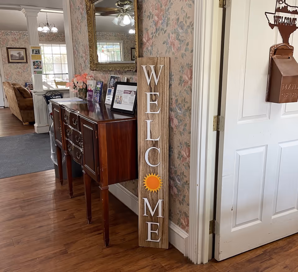 Indoor entry area of a senior living facility with a Welcome sign and wooden console.