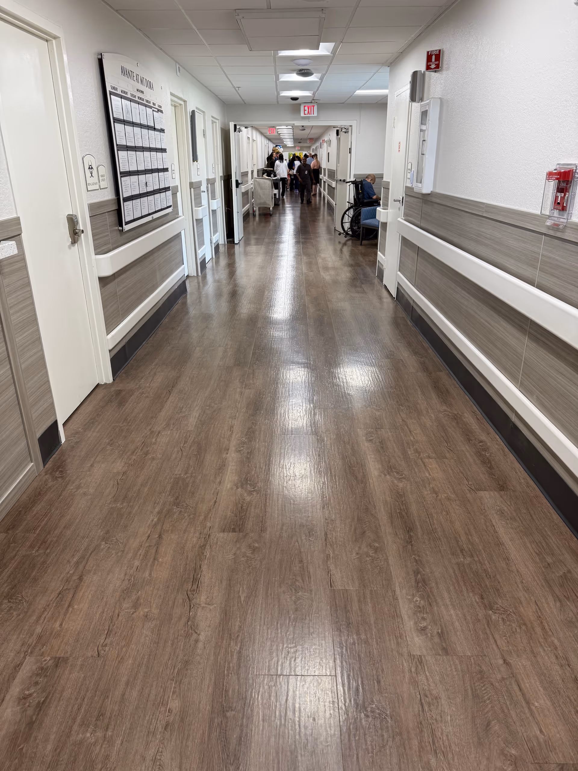 Long interior corridor in Avante at Mt Dora with wood-look flooring and handrails.